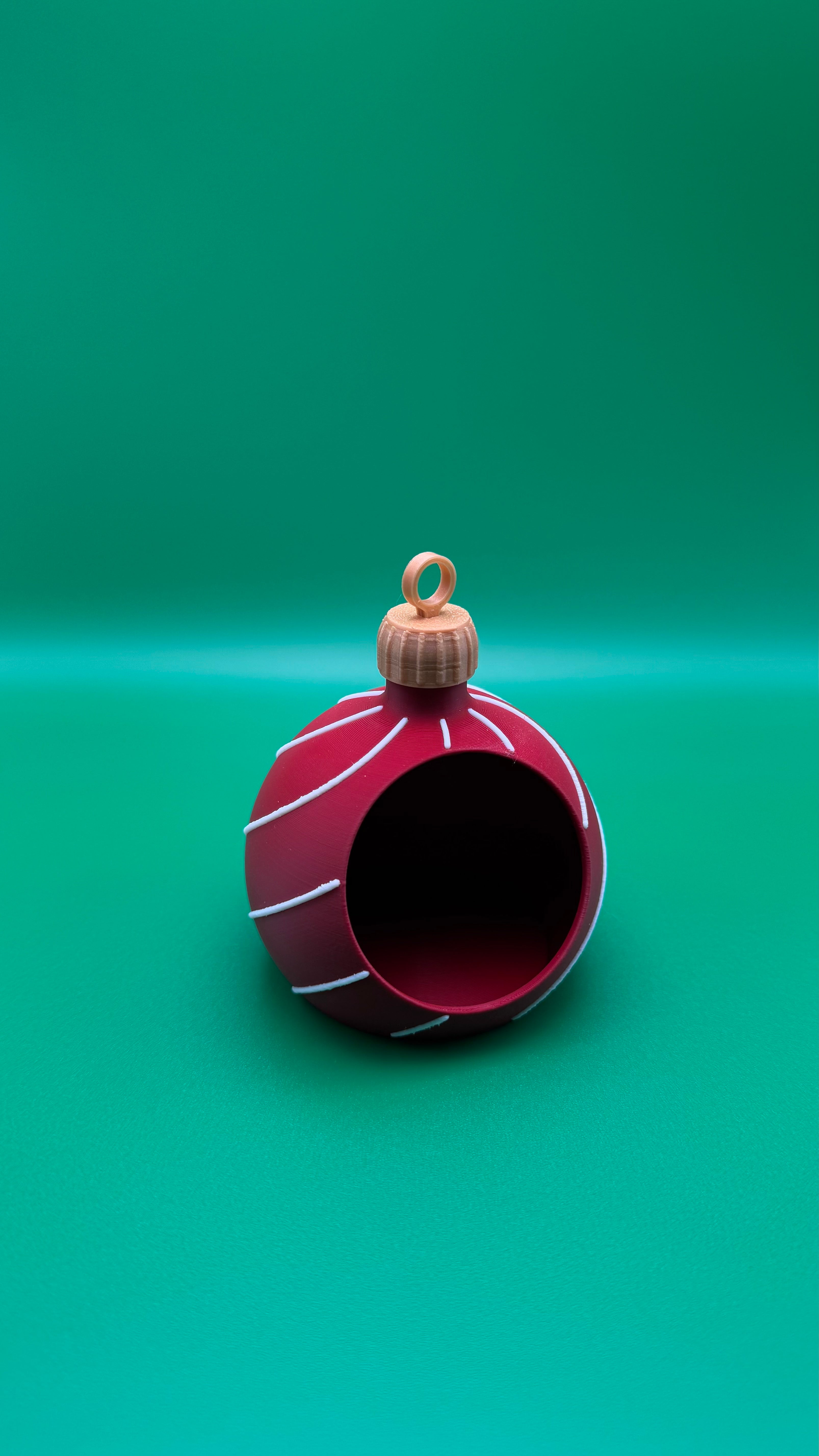 Red Christmas ornament with white stripes on a green background