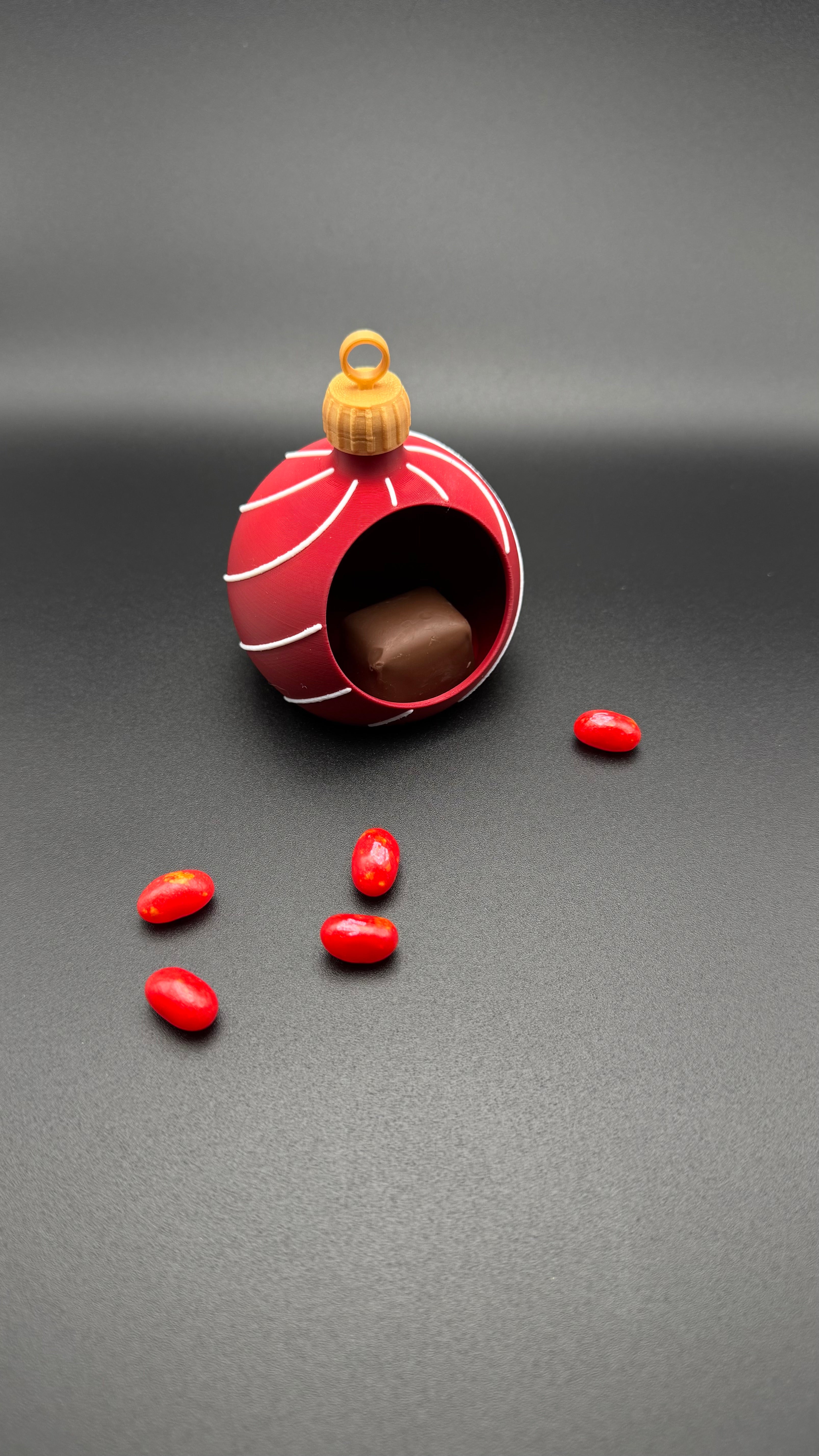 A red and white striped ornament gift holder with gold ring twisty top