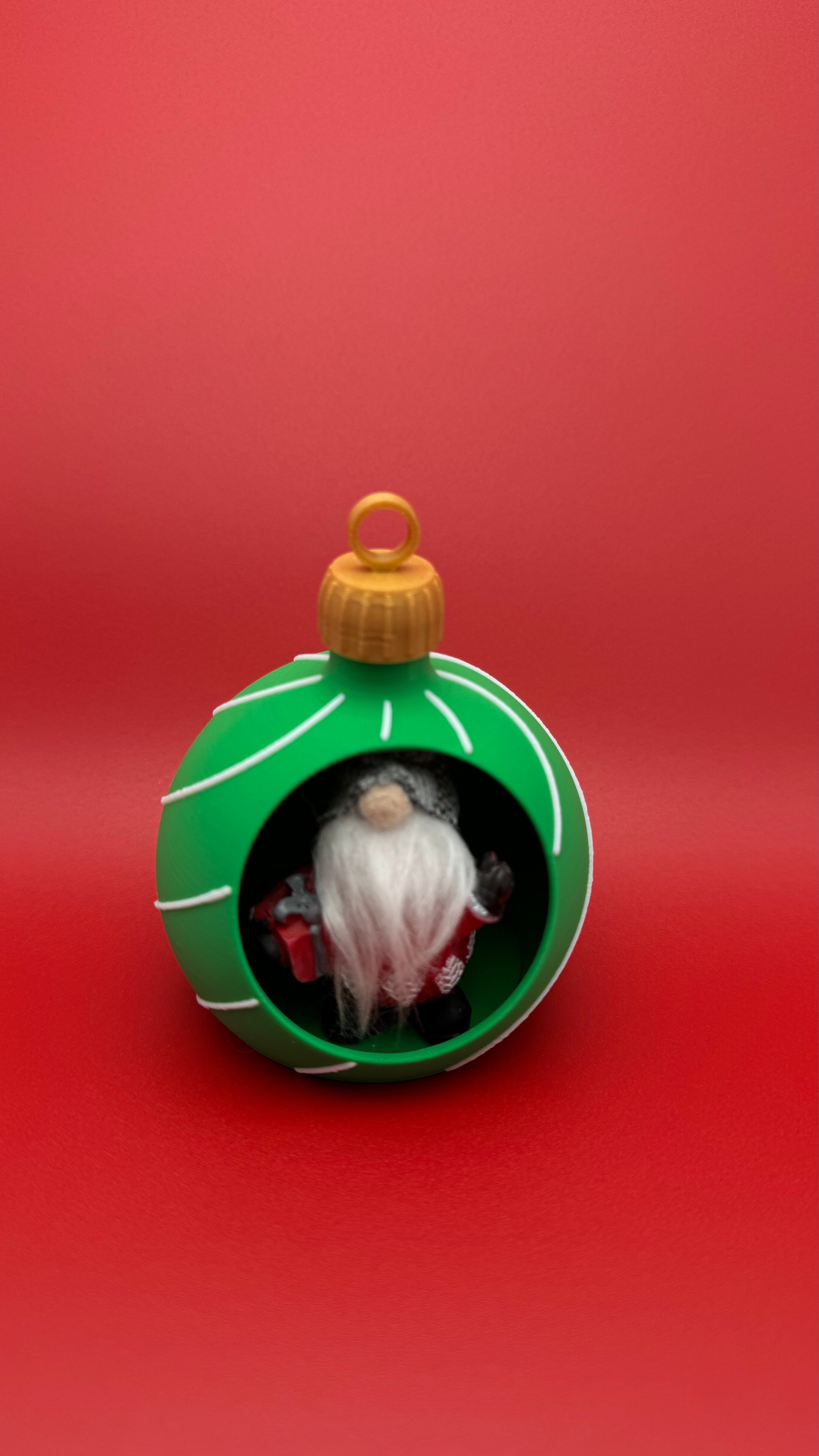 Green Christmas ornament with a Santa Claus figure inside on a red background